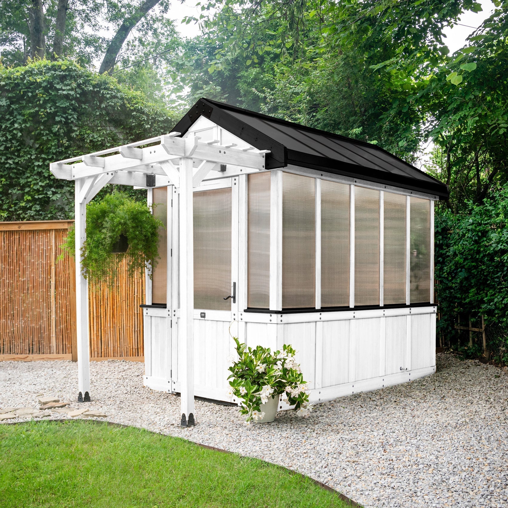 Backyard Discovery Bellerose white cedar greenhouse with a trellis roof installed on a level compacted gravel foundation.