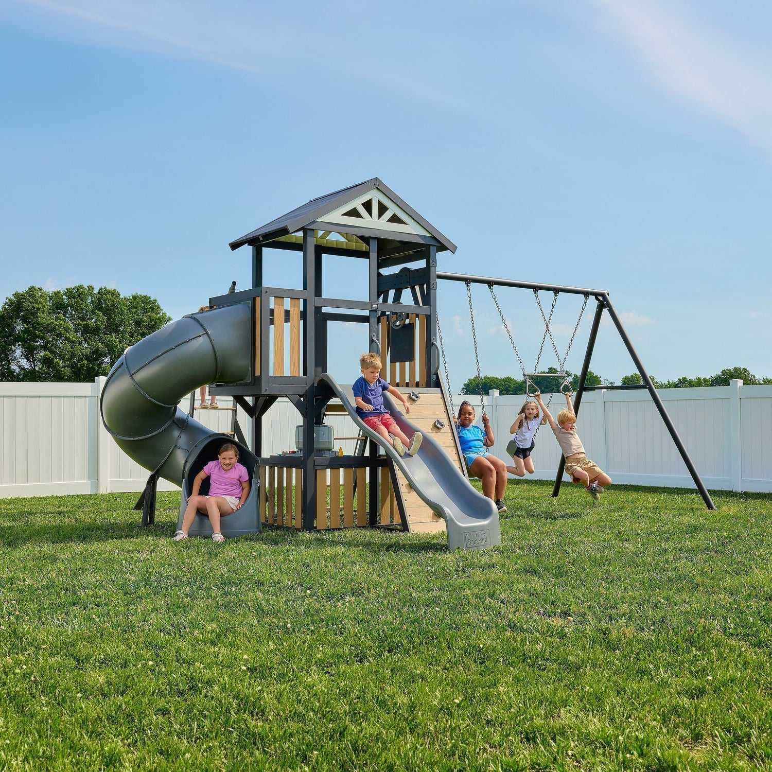 The Atlas modern metal swing set with a square powder-coated steel frame, tube slide, wave slide, and monkey bars in a residential backyard.