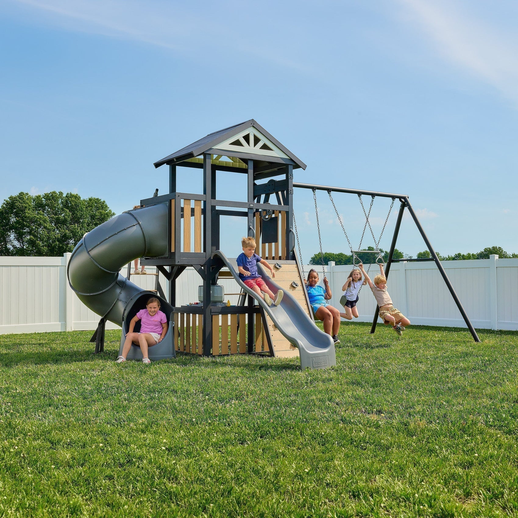 The Atlas modern metal swing set with a square powder-coated steel frame, tube slide, wave slide, and monkey bars in a residential backyard.