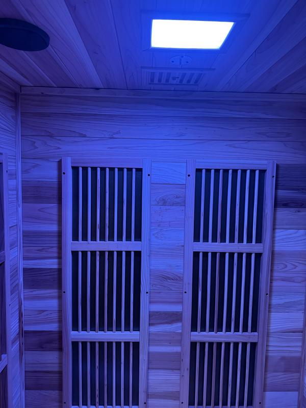 Infrared sauna with wooden walls and ceiling, featuring a light fixture.