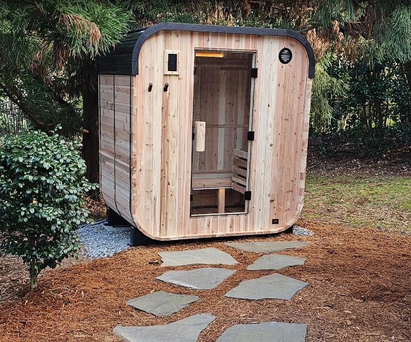 Wooden outdoor sauna with stone pathway in a natural setting