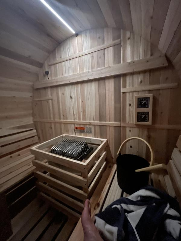 Wooden sauna interior with a person holding a towel