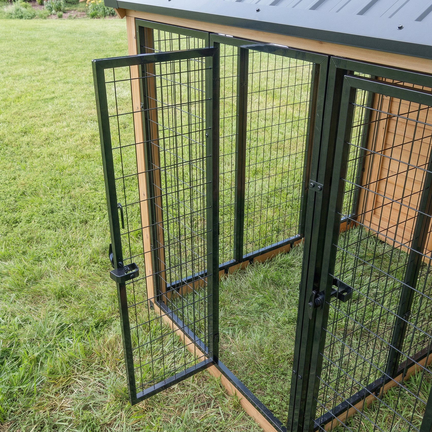 Open mesh gate door on Backyard Discovery cedar and steel outdoor pet enclosure on grass.