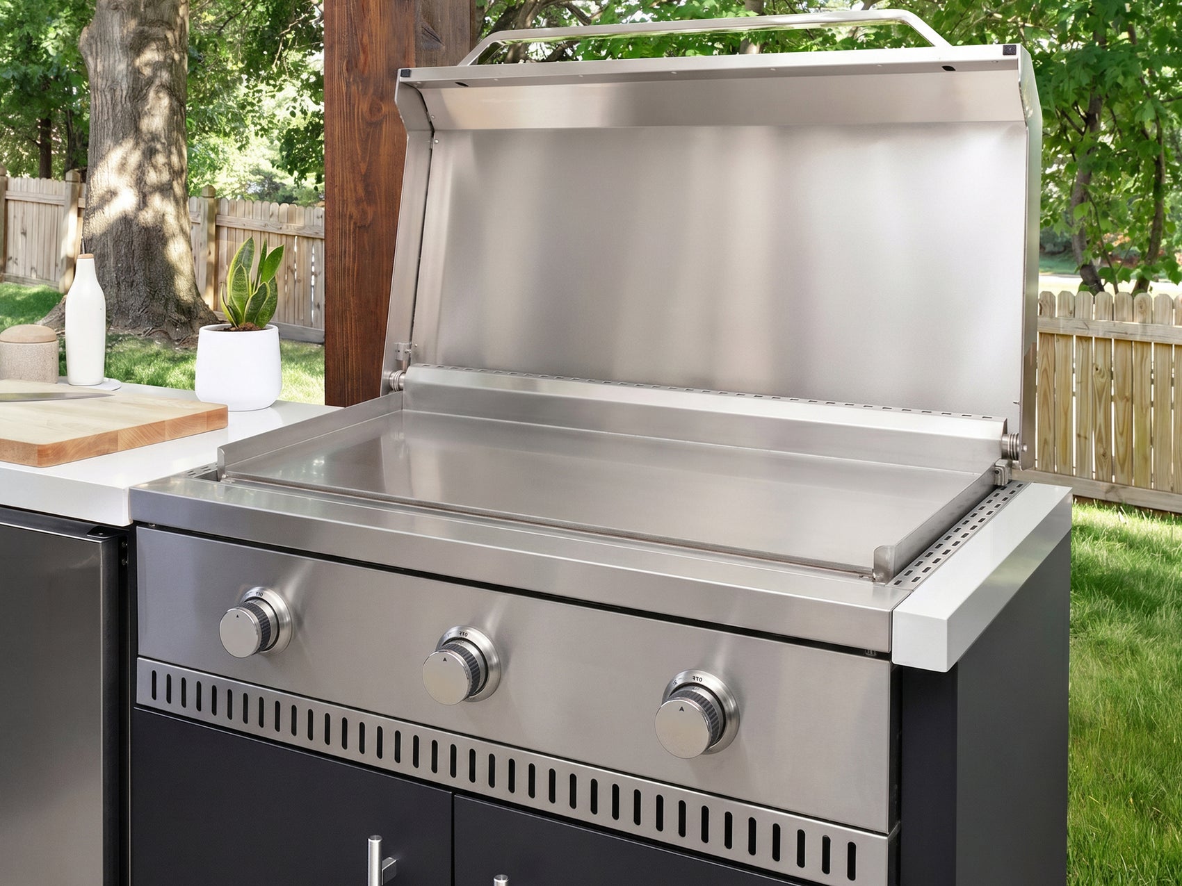 Flat top griddle made from stainless steel with three control knobs built into the Emory outdoor kitchen island.