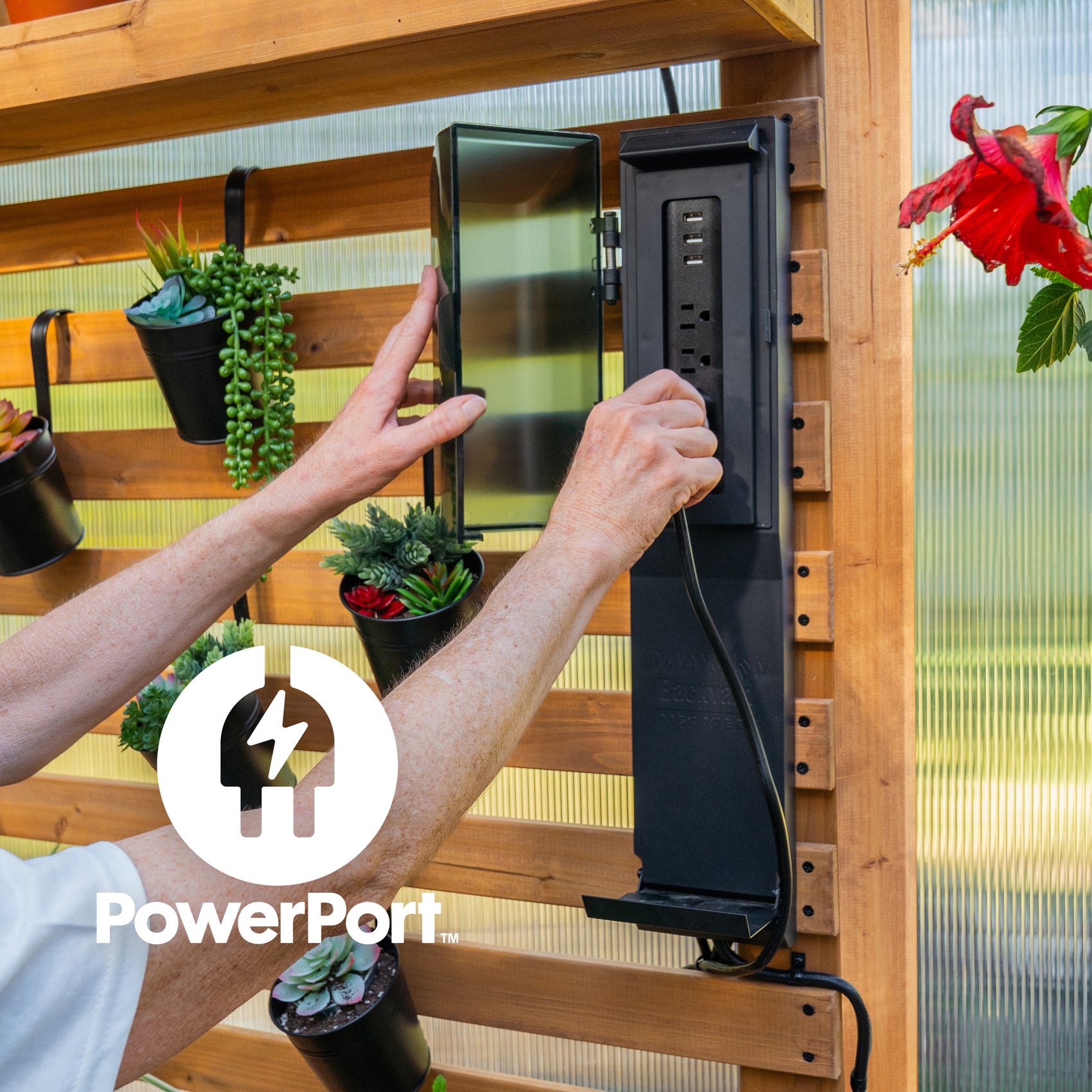 Person opening the outdoor-rated PowerPort electric hub with 3 outlets and 3 USB ports inside Backyard Discovery greenhouse.