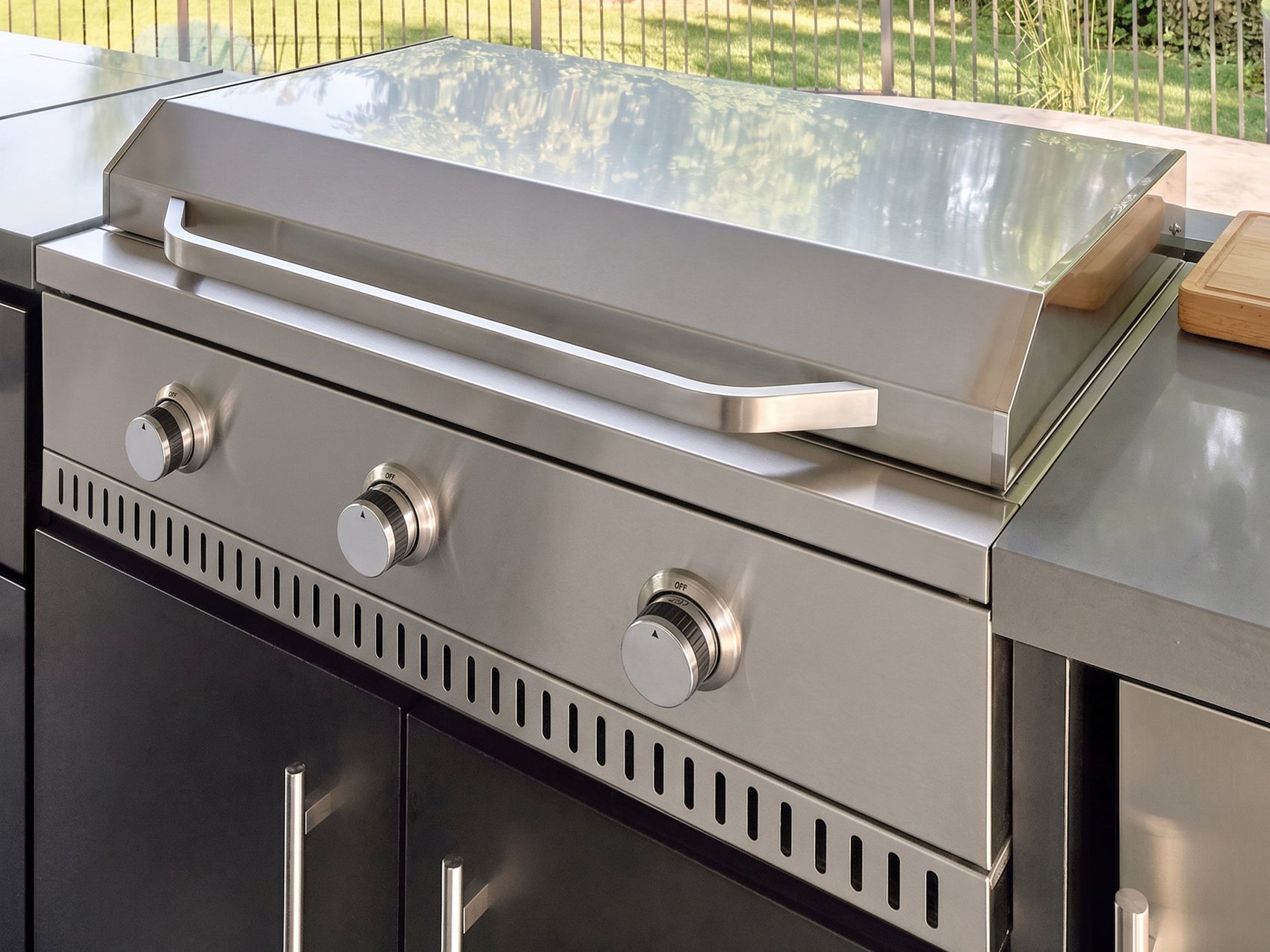 Outdoor griddle made from stainless steel with three control knobs in the Lancaster L-Shape galvanized steel cabinet.