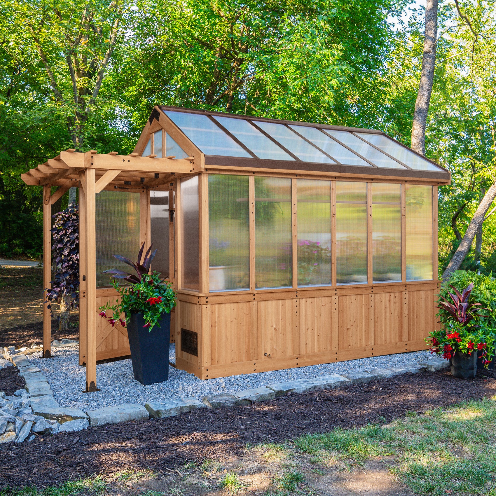 Bellerose cedar-frame greenhouse shed with polycarbonate panels set in a landscaped backyard with colorful plants.