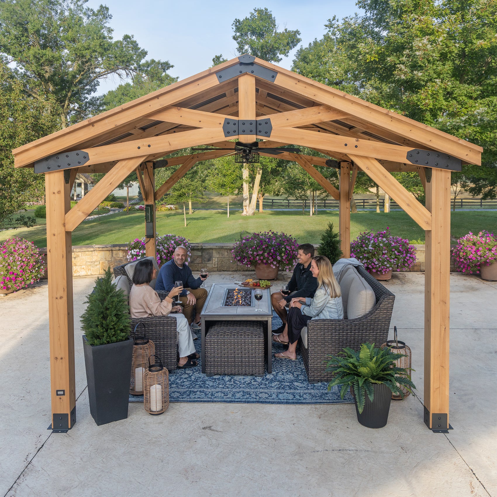 Steel frame gazebo with cedar beams and arched trusses over outdoor seating area with fire table in backyard.