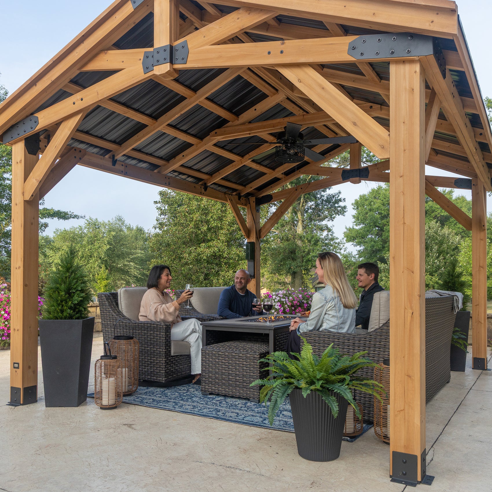 Cedar posts and steel panels on backyard gazebo sheltering outdoor patio seating area with ceiling fan.