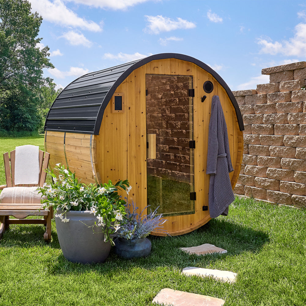 Paxton 2-4 person outdoor barrel cedar sauna with black steel roof and glass door in sunny backyard