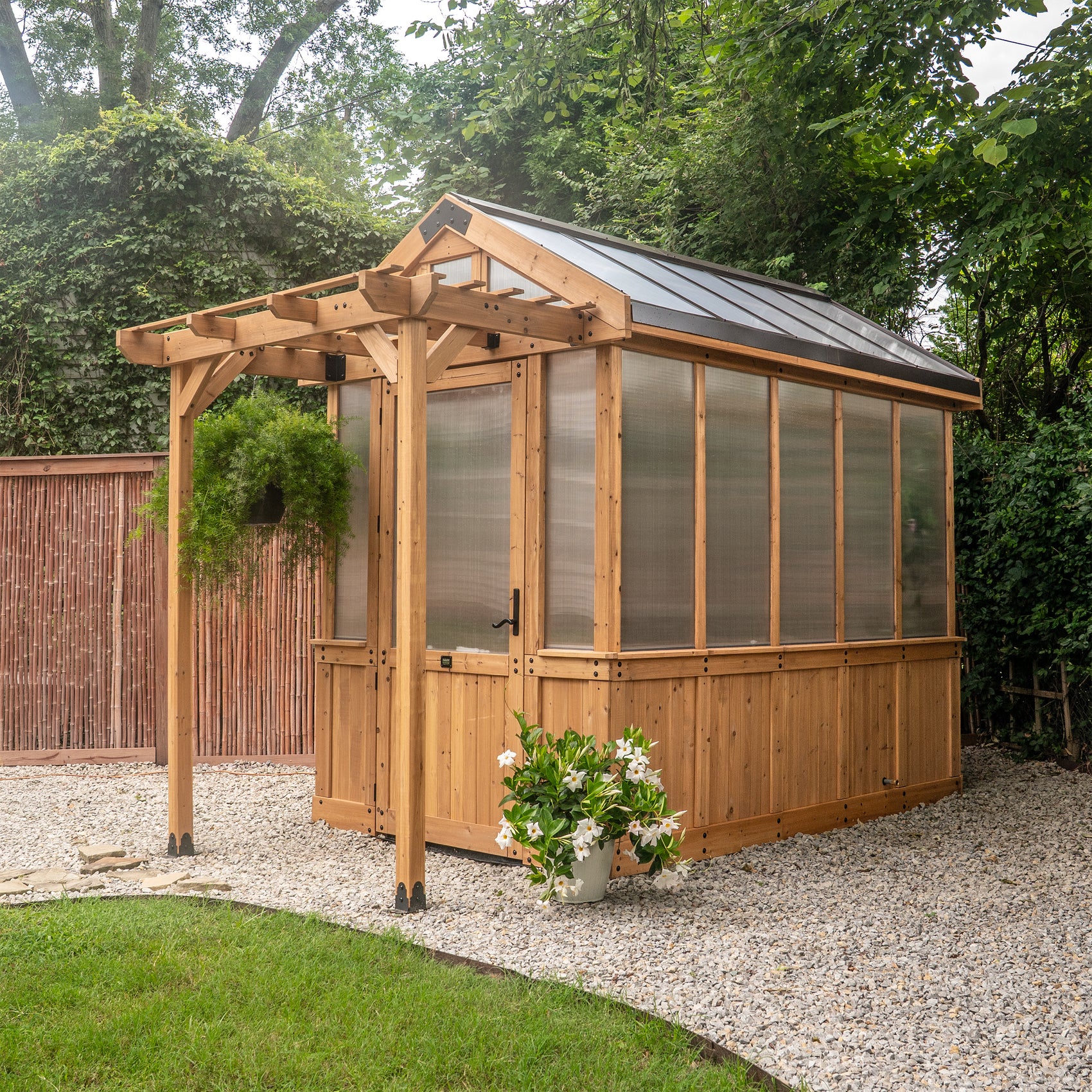 Backyard Discovery Bellerose 9x6 outdoor greenhouse with a peaked roof, pergola overhang, wide entry door.