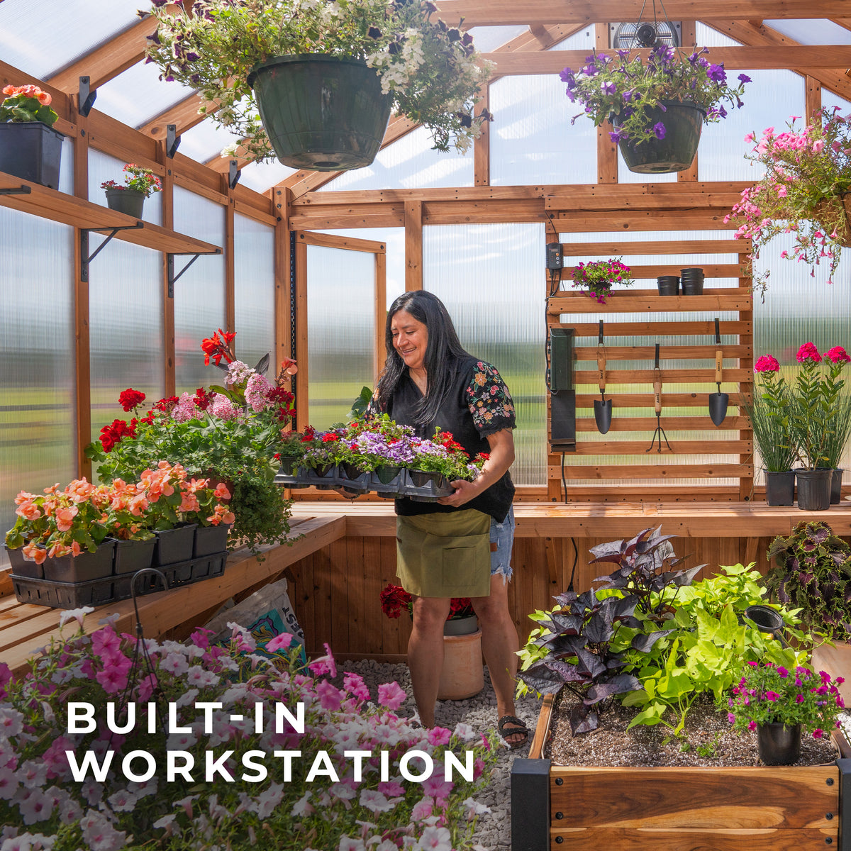 Woman arranging flower trays at the built-in workstation inside the Bellerose XL cedar greenhouse.