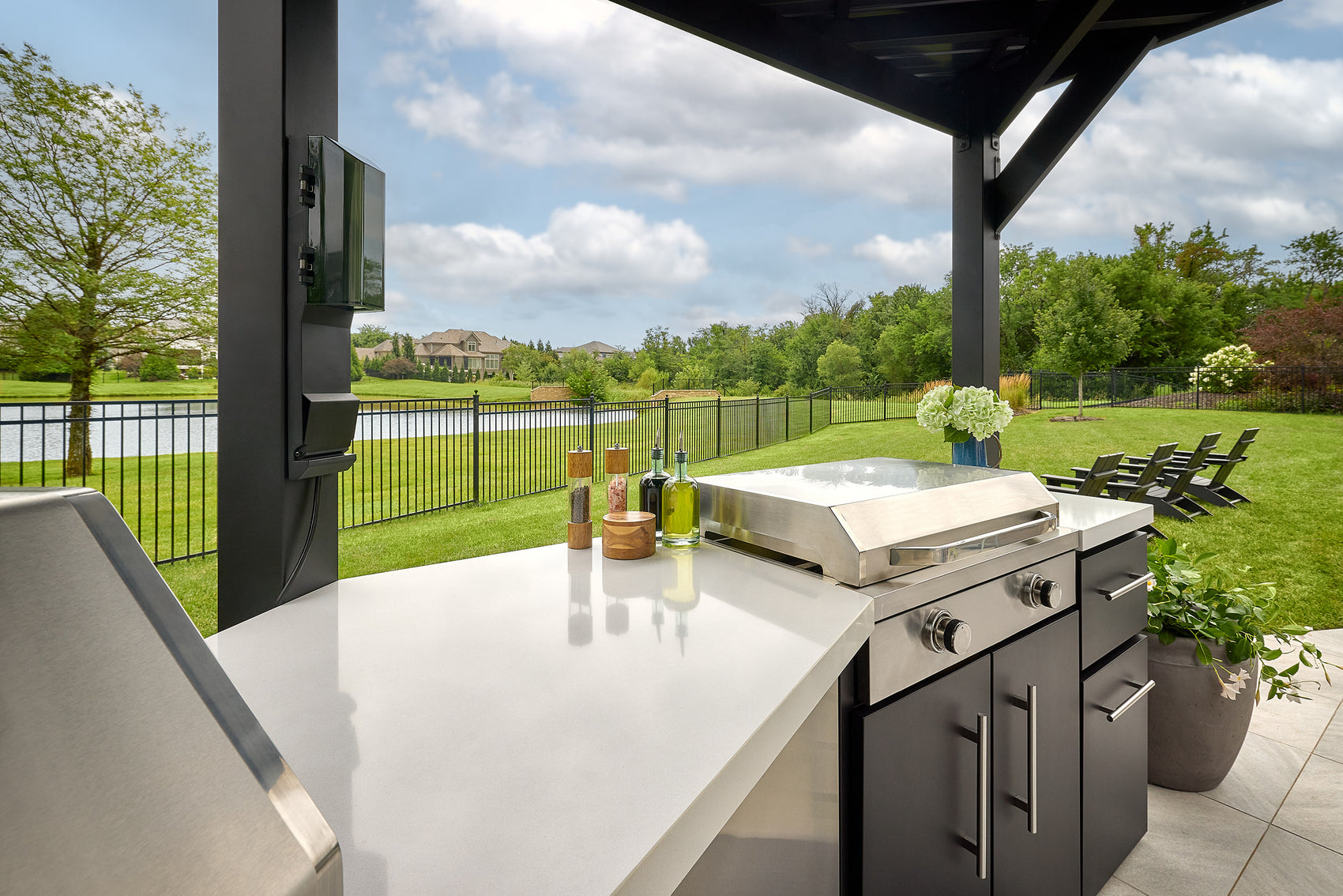 Edgemont Cove Outdoor Kitchen lower cabinet door open revealing built-in paper towel holder with roll installed, pizza oven and grill visible in background
