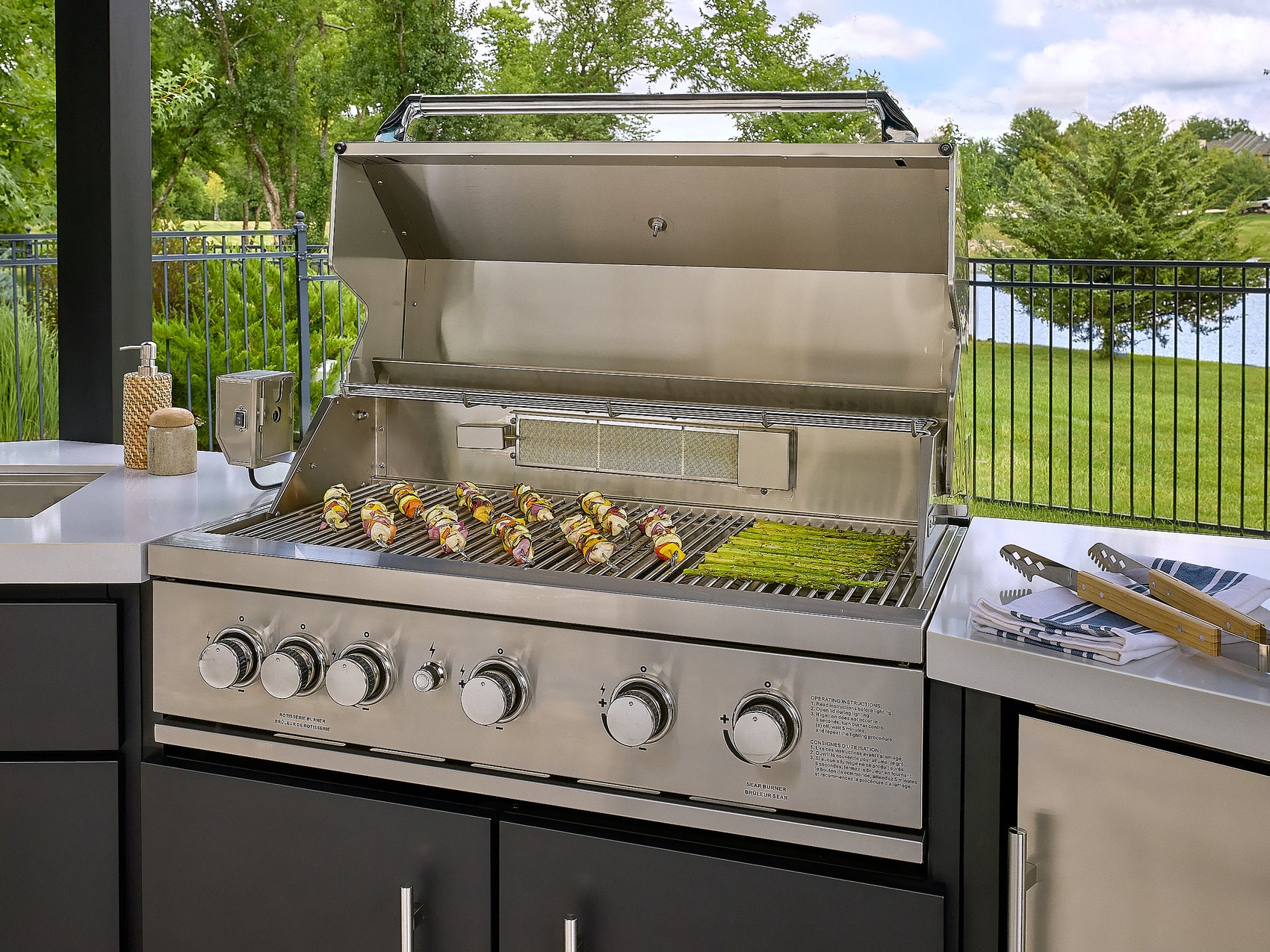 Angled view of the Edgemont Cove Outdoor Kitchen pergola roof structure showing slatted aluminum roof panels and post-and-beam frame, with full kitchen visible below