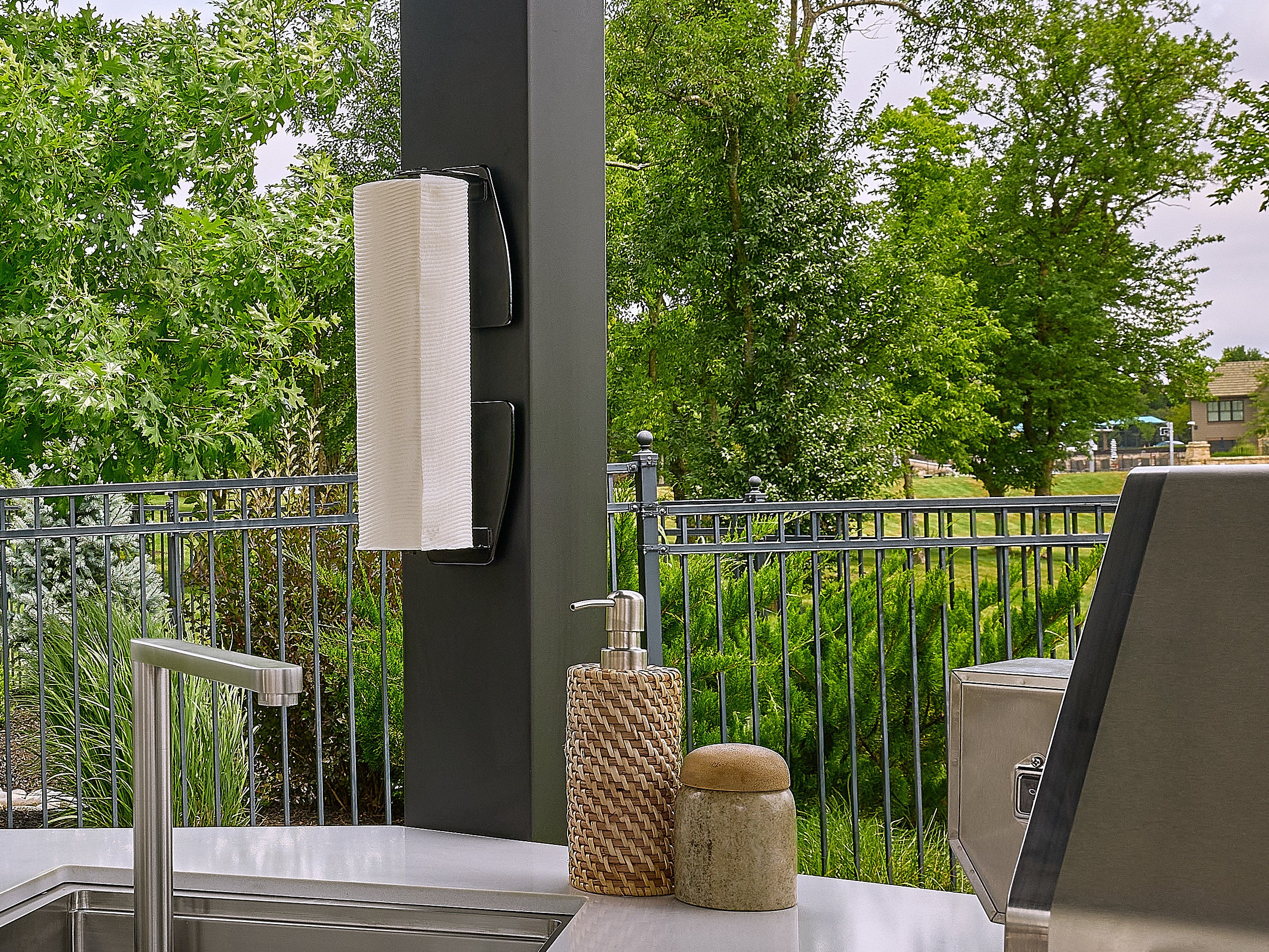 Group of friends dining at an outdoor table while one person retrieves a drink from the Edgemont Cove Outdoor Kitchen under-counter refrigerator