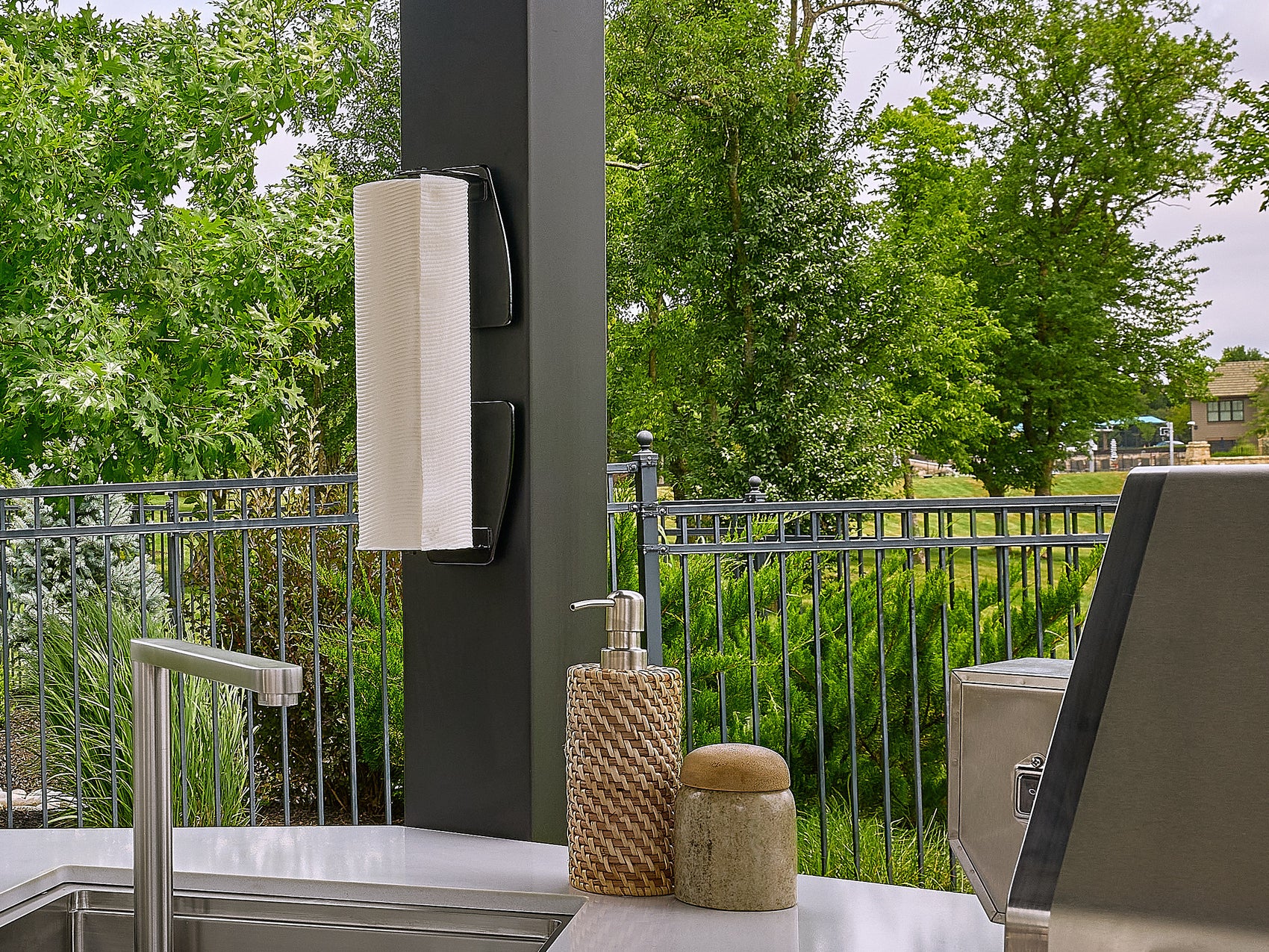 Group of friends dining at an outdoor table while one person retrieves a drink from the Edgemont Cove Outdoor Kitchen under-counter refrigerator