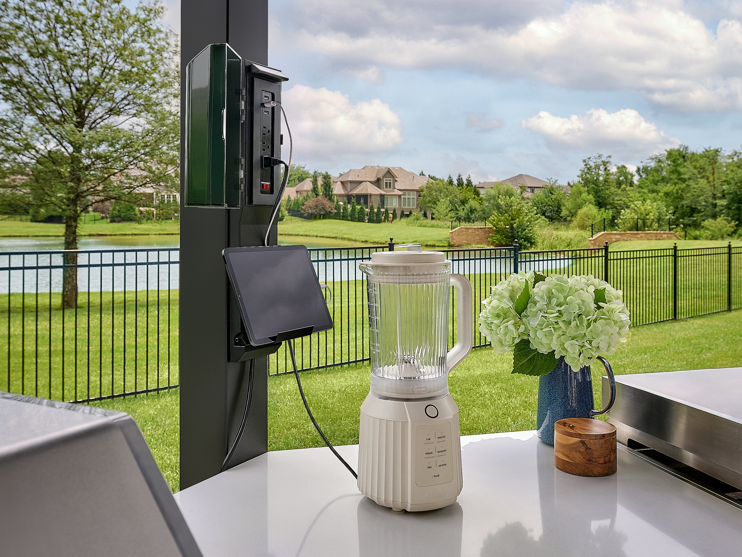 Edgemont Cove Outdoor Kitchen stainless steel built-in gas grill with lid open, showing grill grates and rotisserie bar, mounted in dark charcoal cabinet base