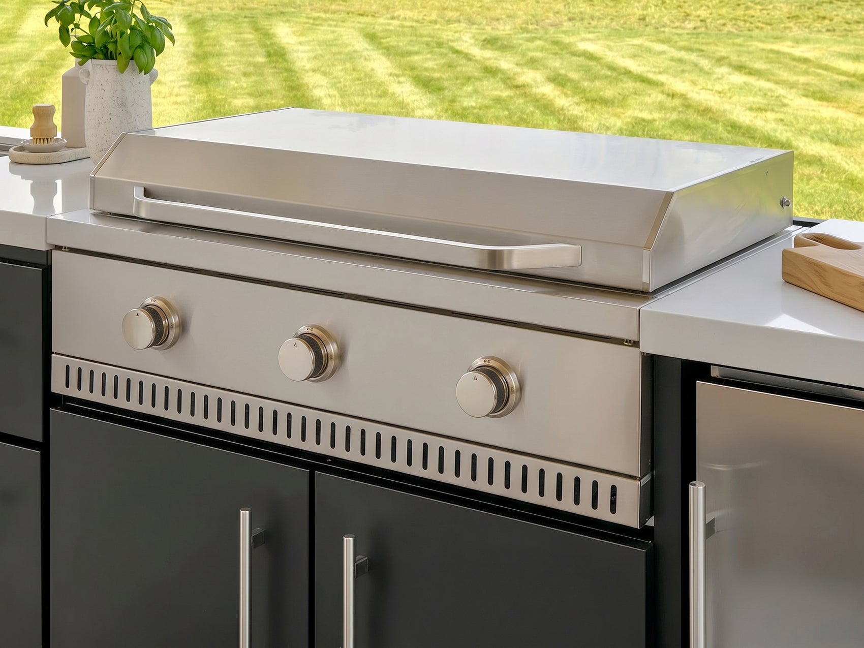 Outdoor griddle made from stainless steel with three burner knobs in the Emory outdoor kitchen.