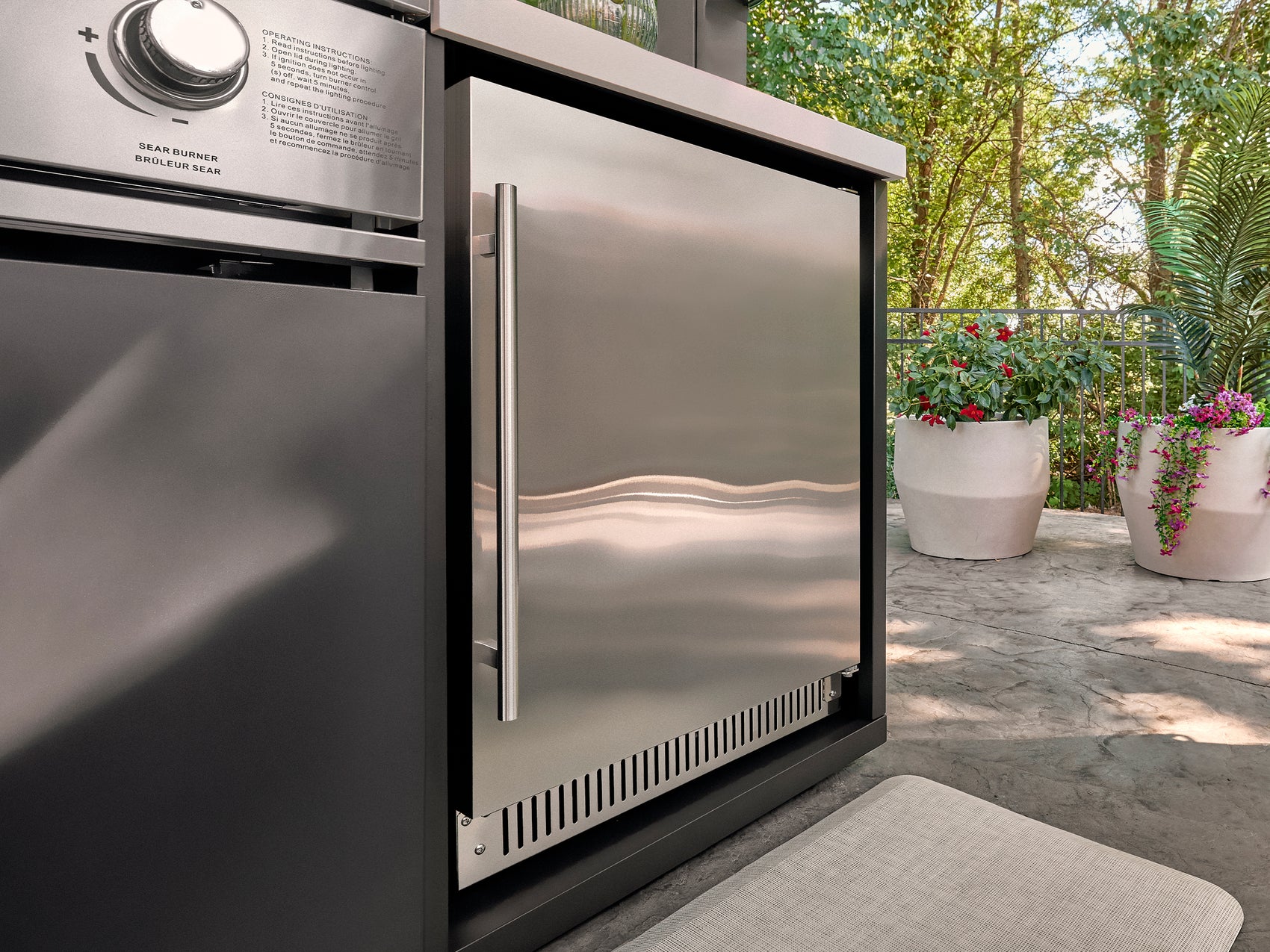 Closed outdoor refrigerator in 304 stainless steel built into L-shaped kitchen island with marble countertop