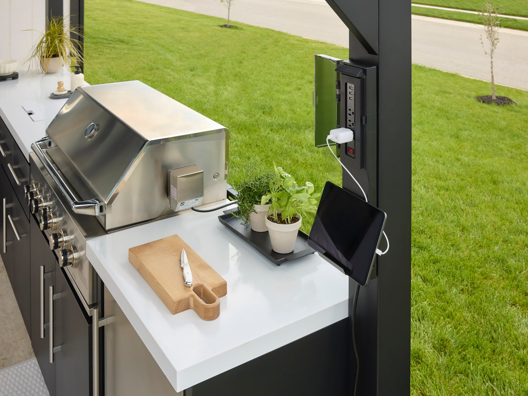 PowerPort charging station with tablet on Lancaster steel outdoor kitchen engineered stone countertop.