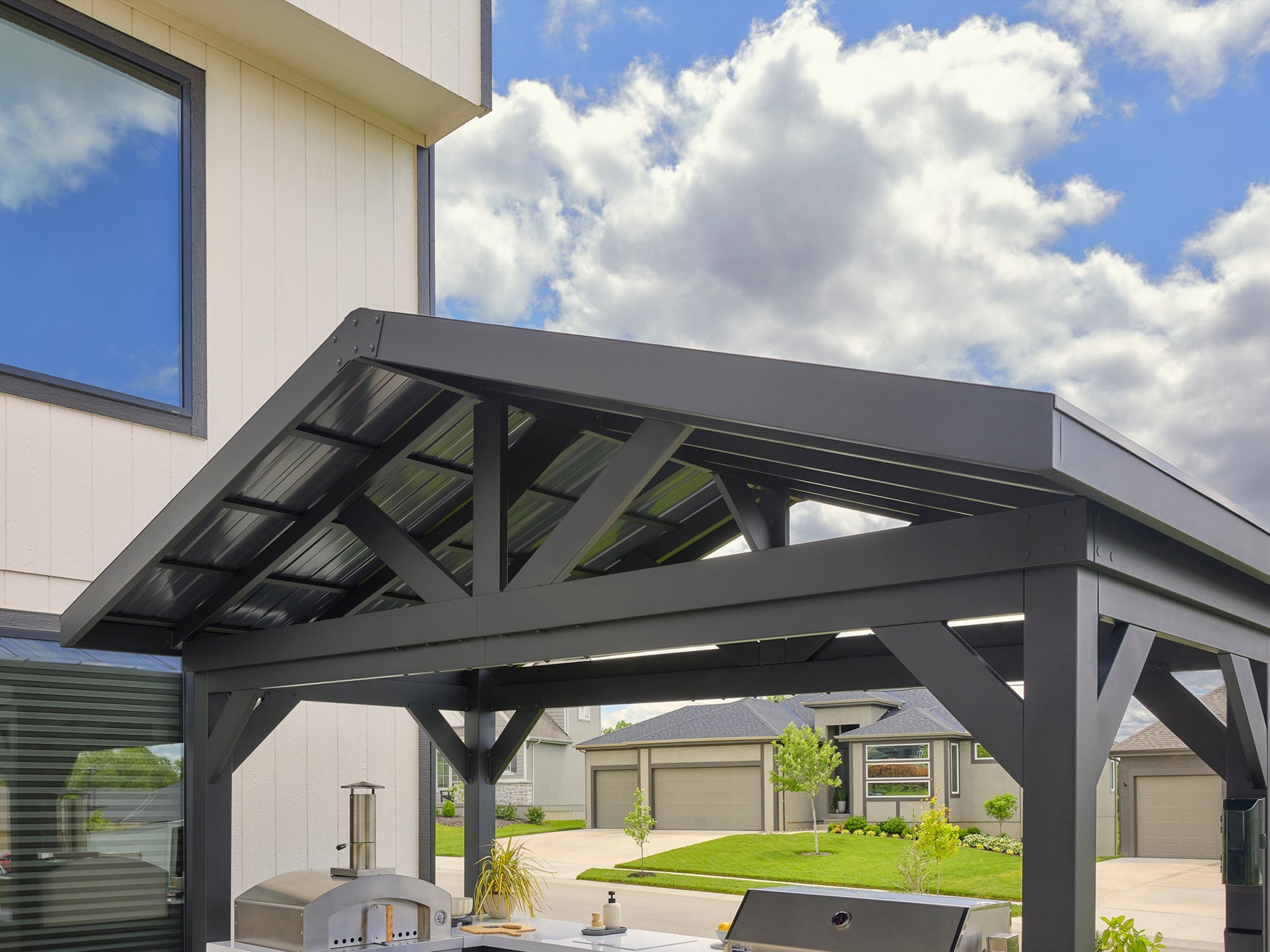 Powder-coated galvanized steel peak roof on covered outdoor kitchen in backyard setting