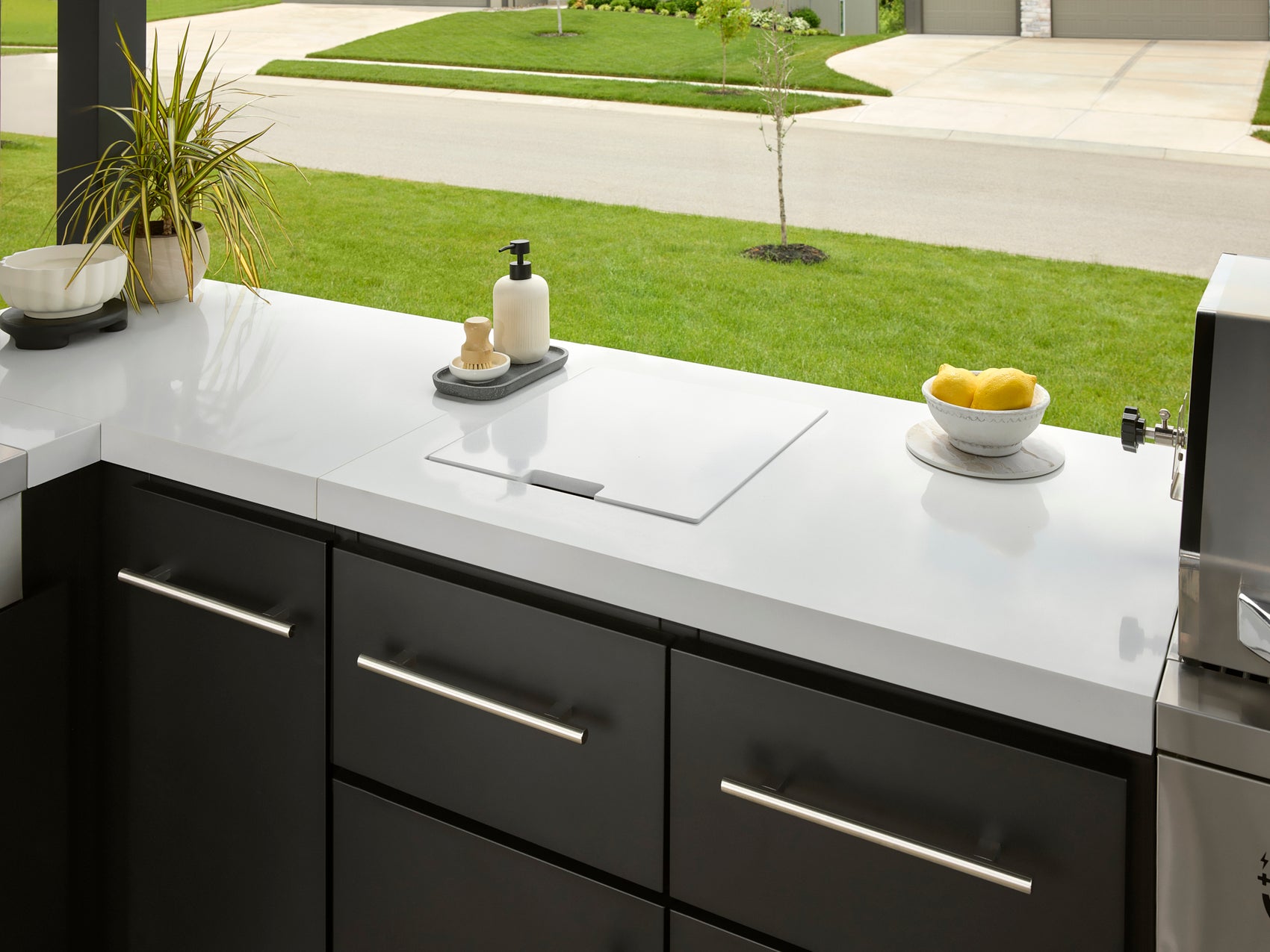 Concealed stow-away sink beneath marble countertop on Lancaster L-shaped outdoor kitchen