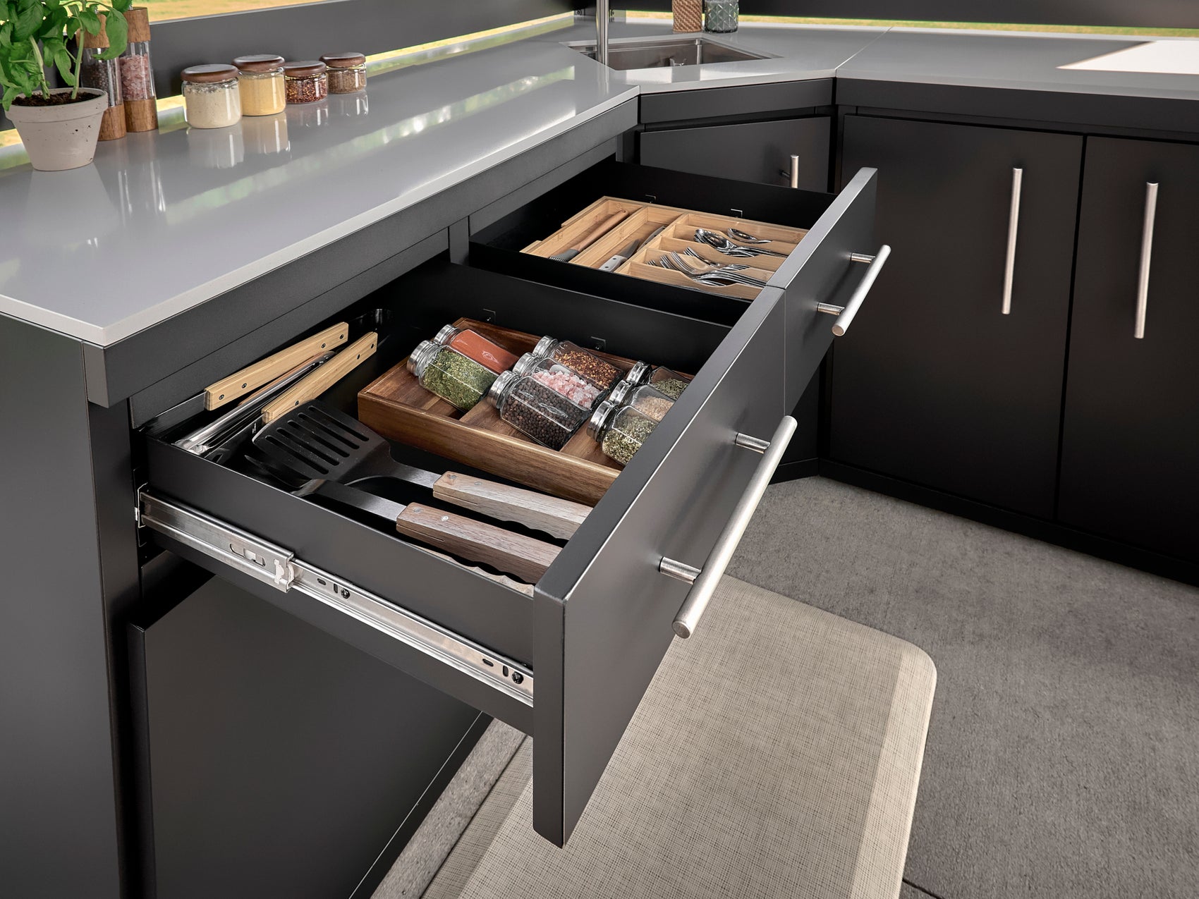 Range Outdoor Living Langston kitchen with open stainless steel cabinet drawers showing utensil organizers, spice jars.