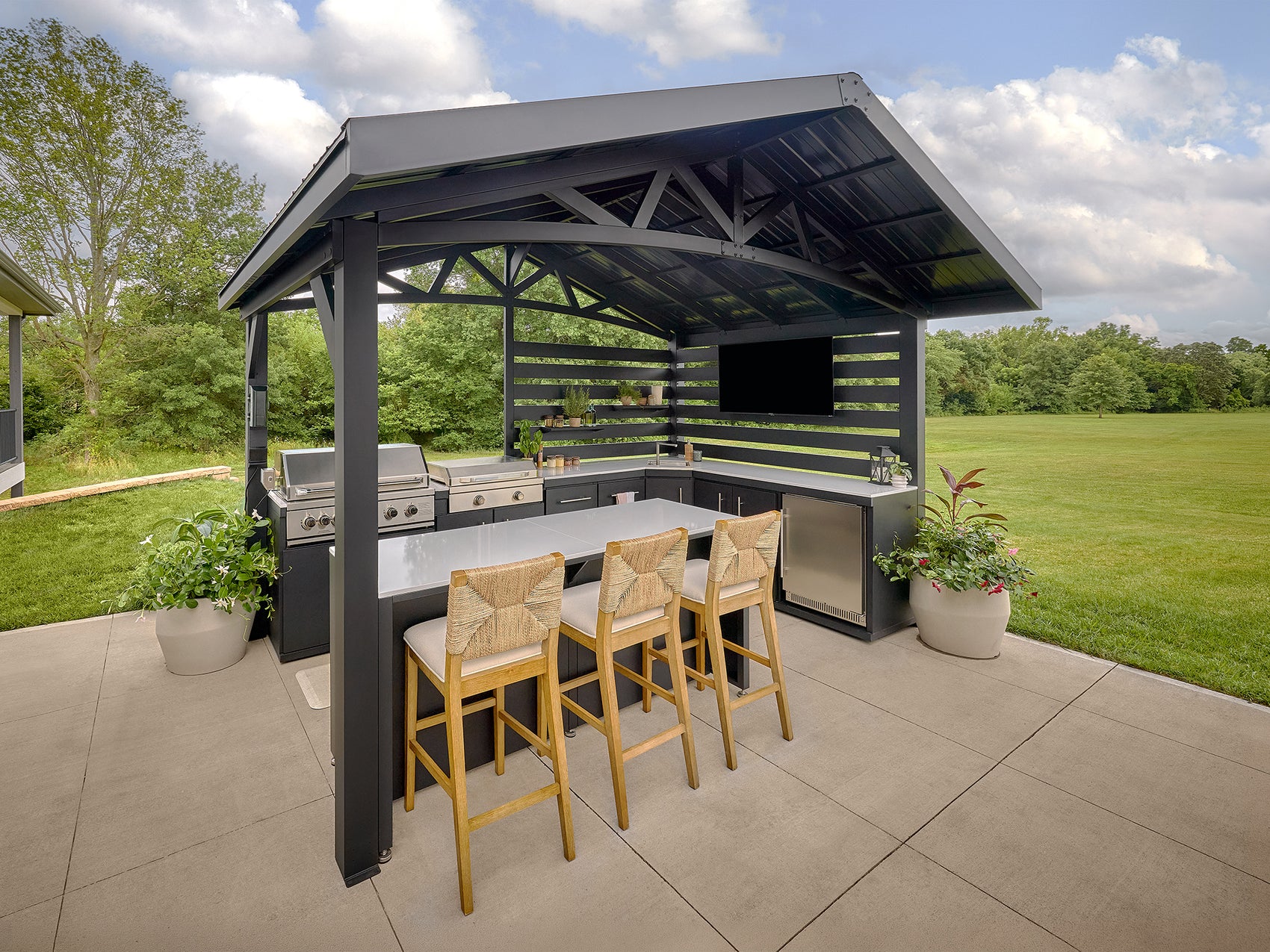 Langston outdoor kitchen under a galvanized steel roof with stainless steel grill, engineered stone countertops.