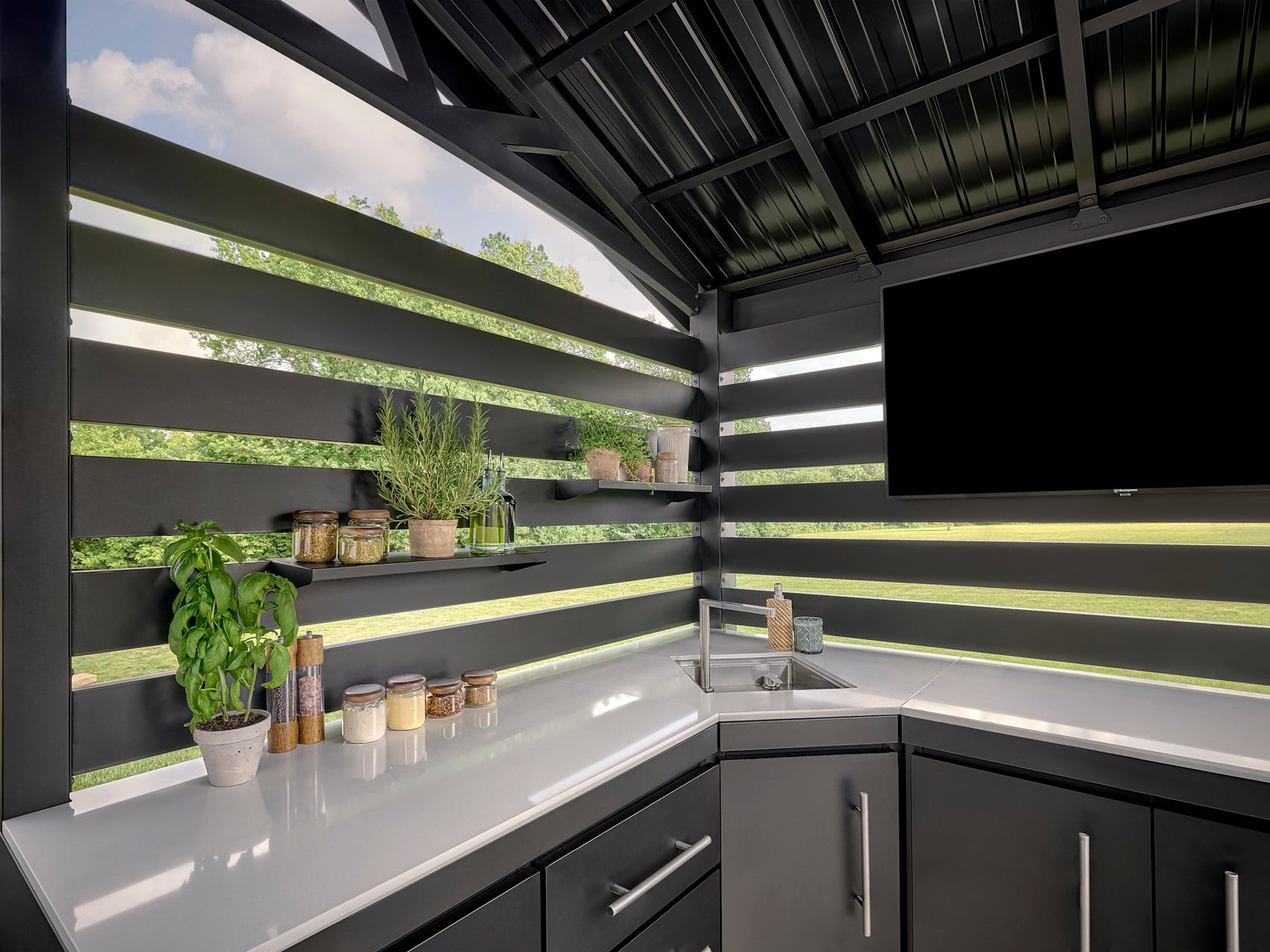 Langston outdoor kitchen with a black steel frame, trellis roof, and white countertops.