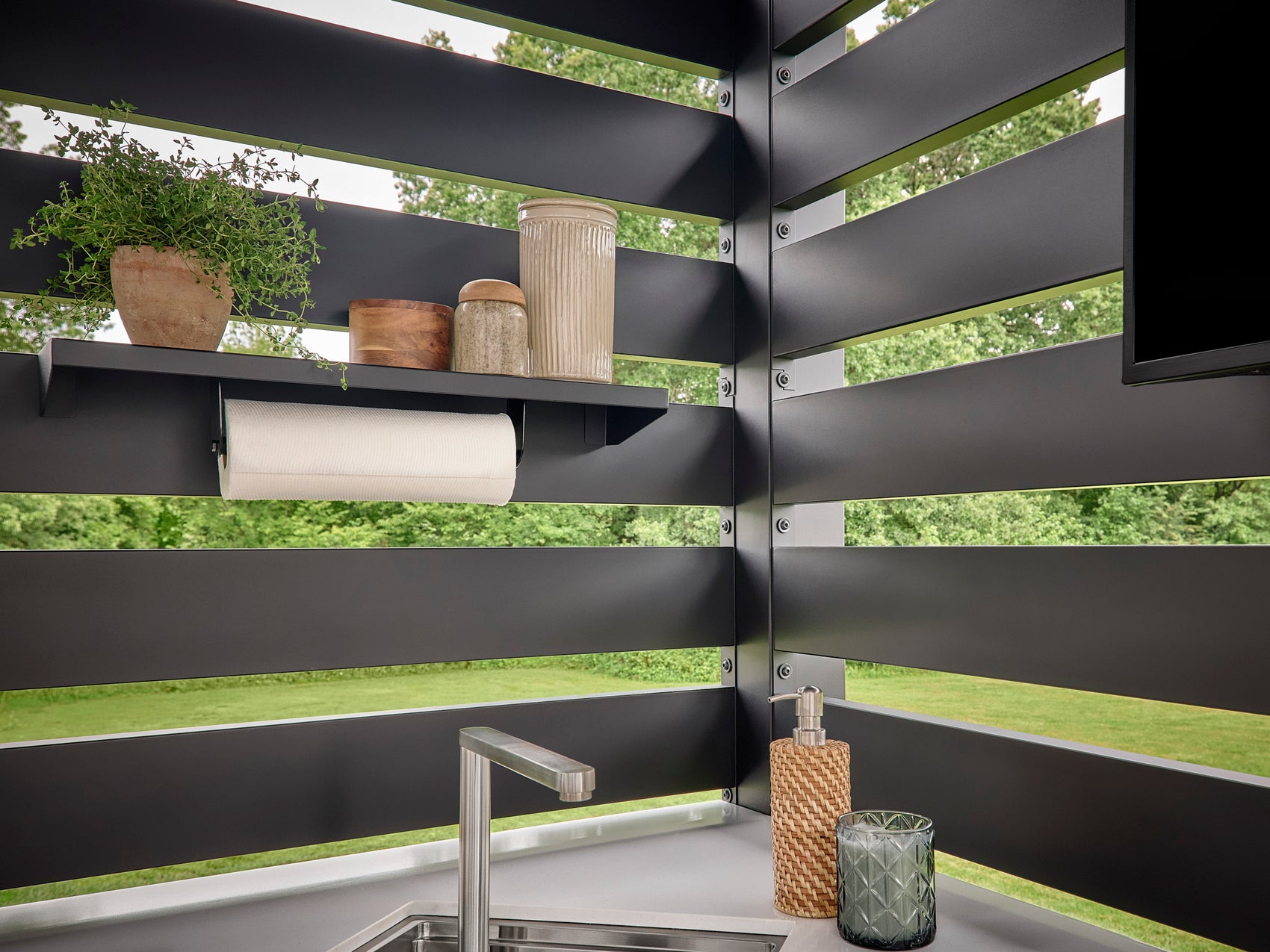 Range Outdoor Living Langston kitchen corner with slat wall, an integrated shelf with a plant, and a paper towel holder.
