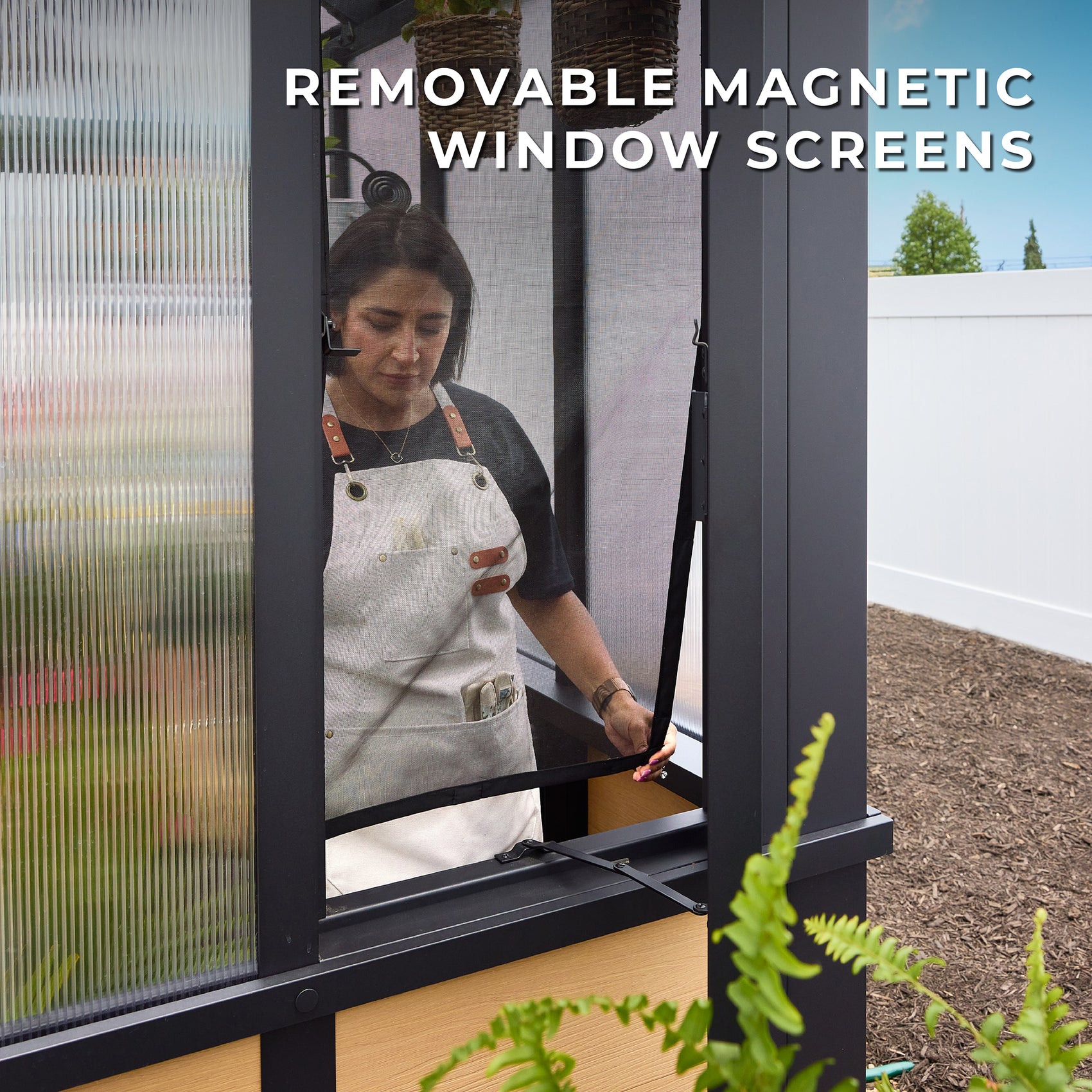Woman removing the included magnetic window screen from an operable window in the Larkspur home greenhouse.