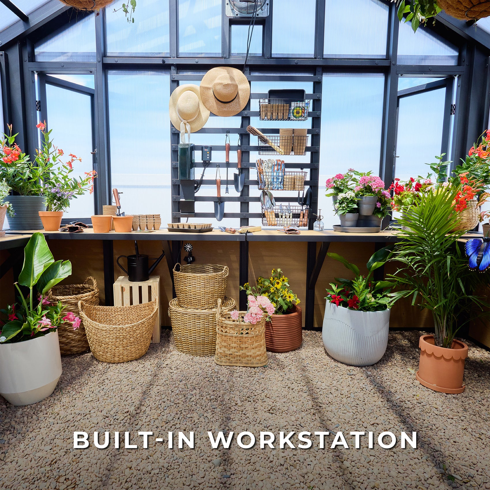 A built-in workstation inside the Larkspur steel greenhouse, with a wood bench, slat wall, hanging tools.