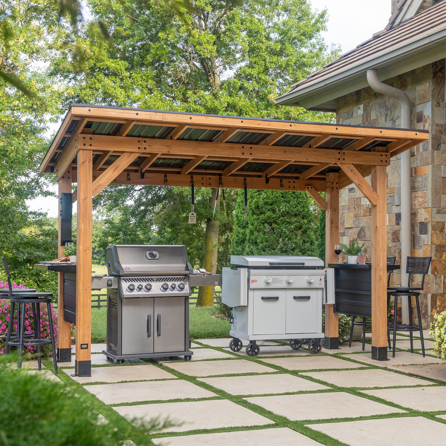 Backyard Discovery grill gazebo in cedar with cantilevered steel roof and bar countertops on stone patio.