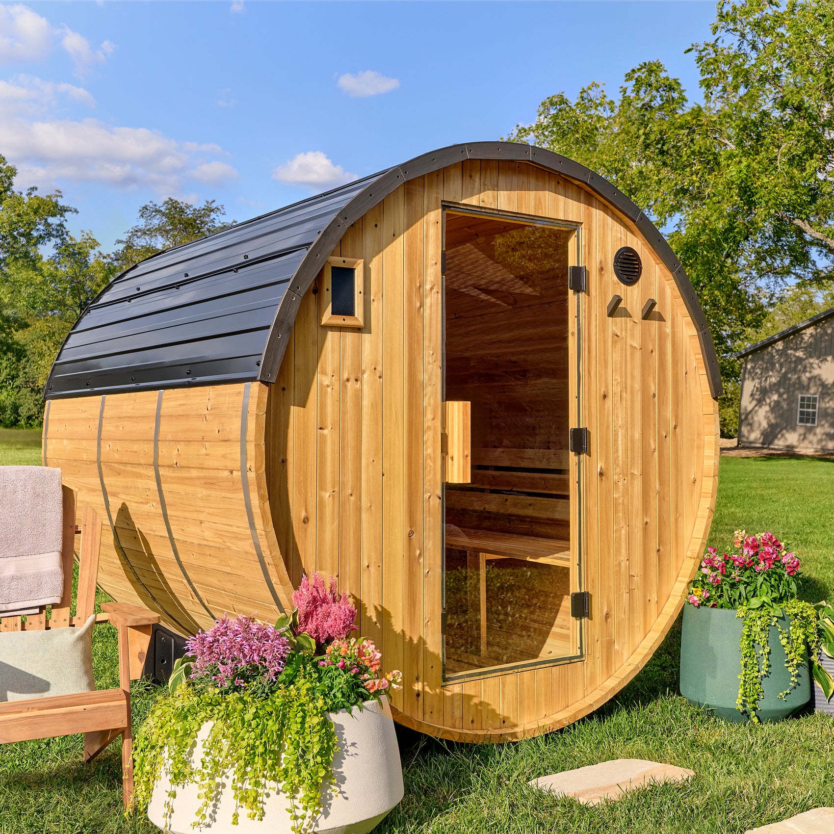 Backyard Discovery Paxton 4-6 person outdoor barrel cedar sauna with steel roof and glass door in backyard