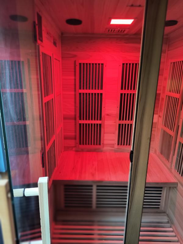 Infrared sauna with red light inside a wooden cabin.