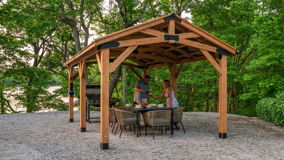 Man and woman grilling under a Backyard Discovery gazebo on a summer evening