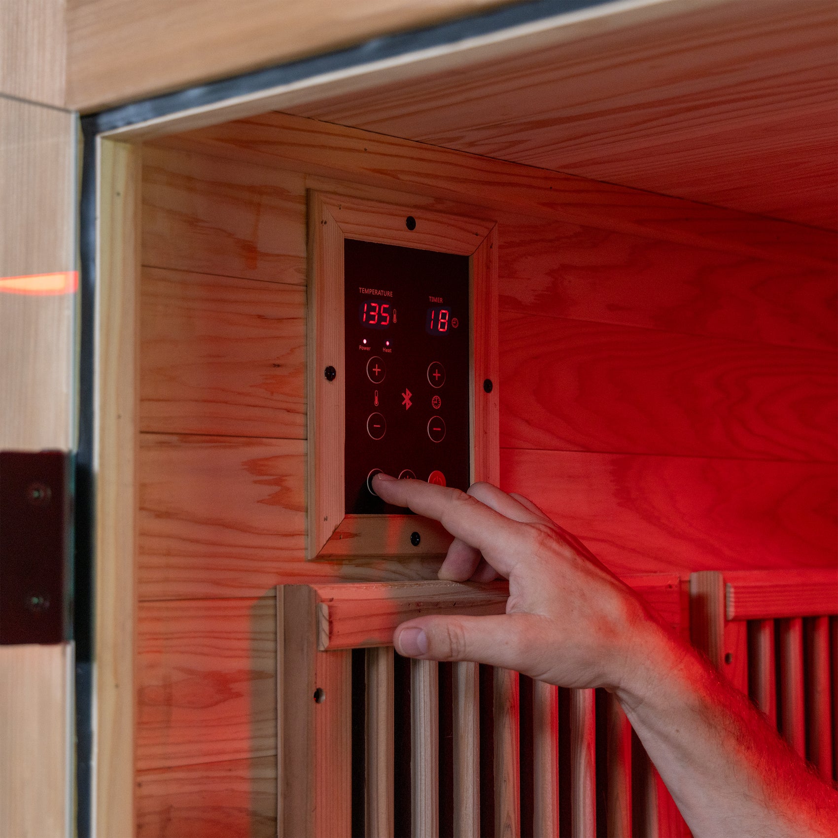 Digital temperature control panel being adjusted inside the Rylan 1 person indoor infrared sauna