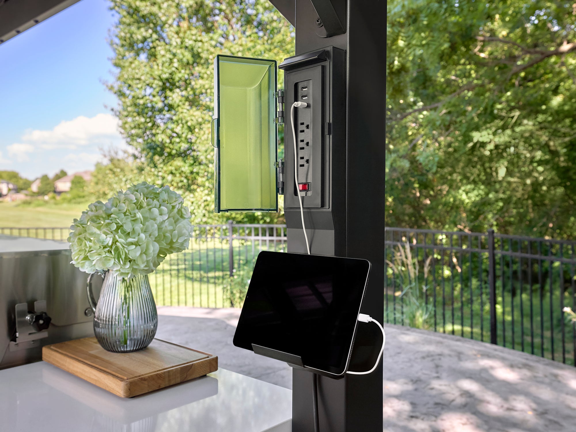 Outdoor power outlet with USB ports and tablet mounted on Lancaster kitchen support column overlooking backyard deck.