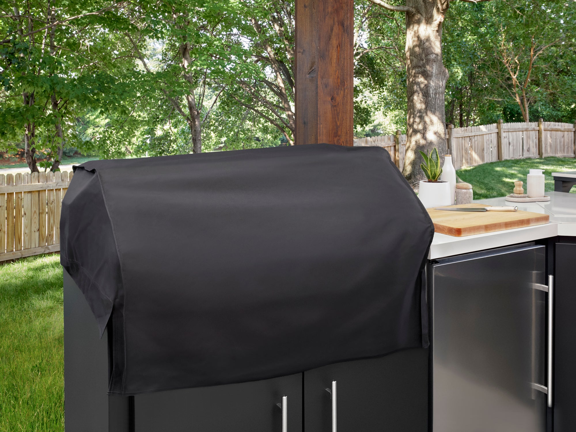 Weatherproof grill cover on patio kitchen island with stainless steel appliances on patio.
