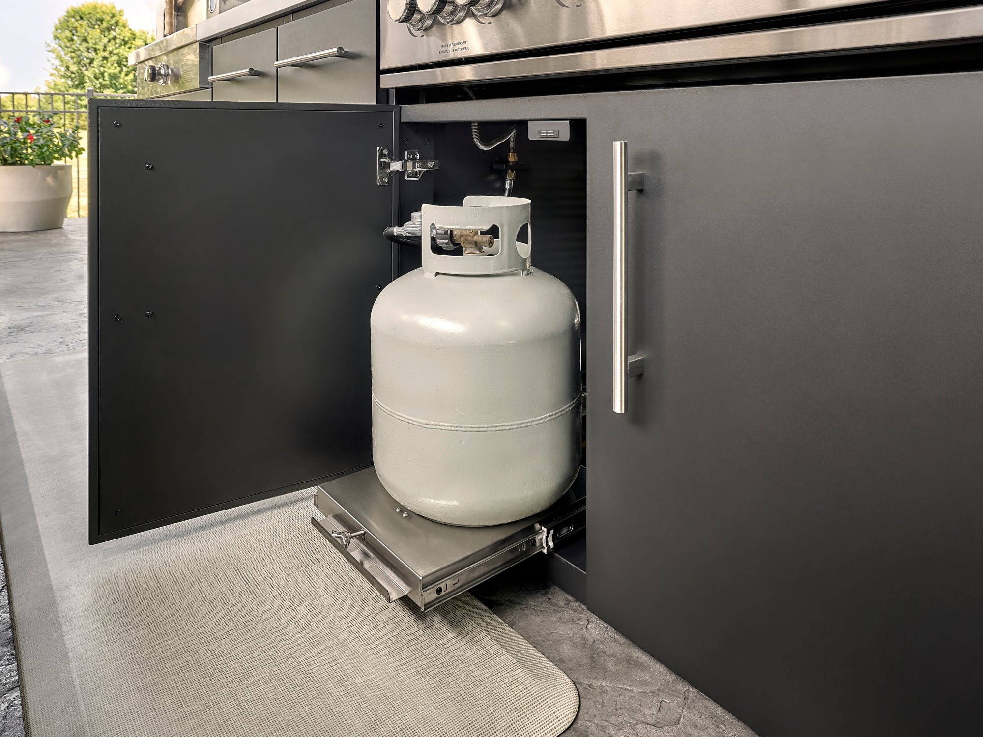 Lancaster Outdoor kitchen cabinet with pull-out propane tank storage drawer beneath built-in grill.