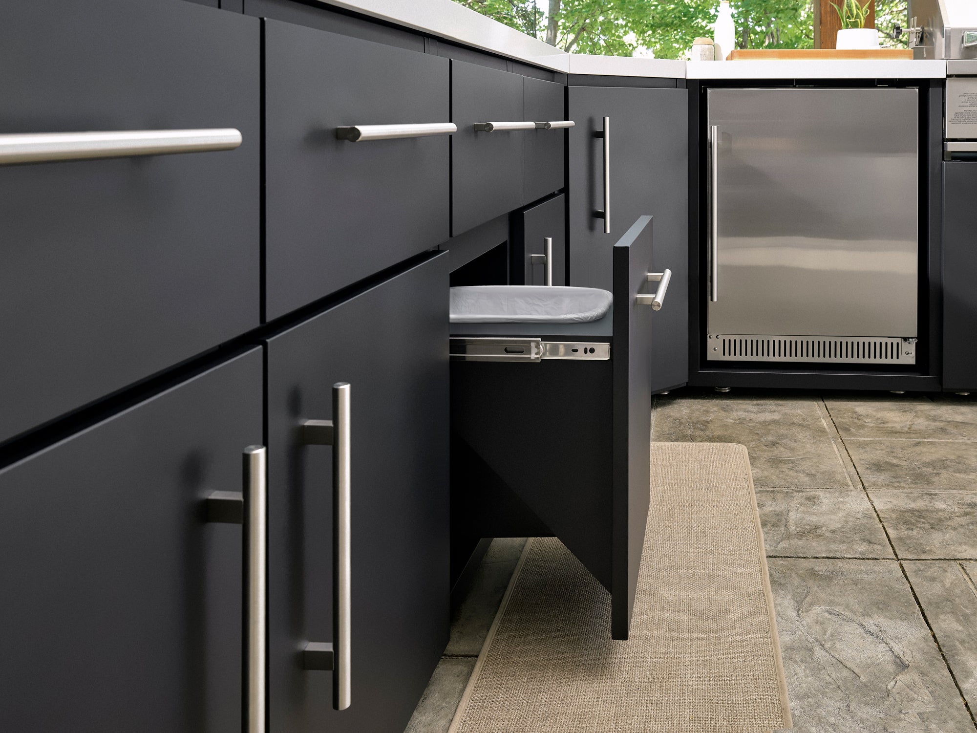 Emory modern outdoor kitchen with dark gray cabinets, brushed steel handles, pull-out trash drawer.