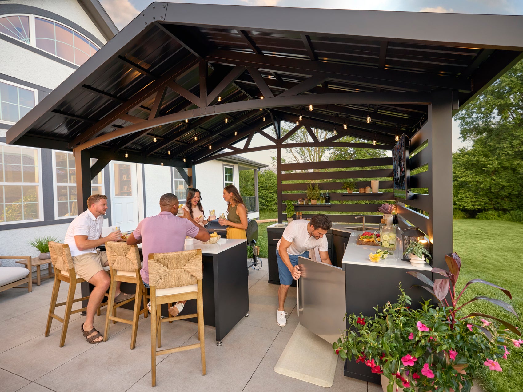 Langston covered outdoor kitchen with built-in bar, grill, refrigerator, and guests gathering for entertaining.