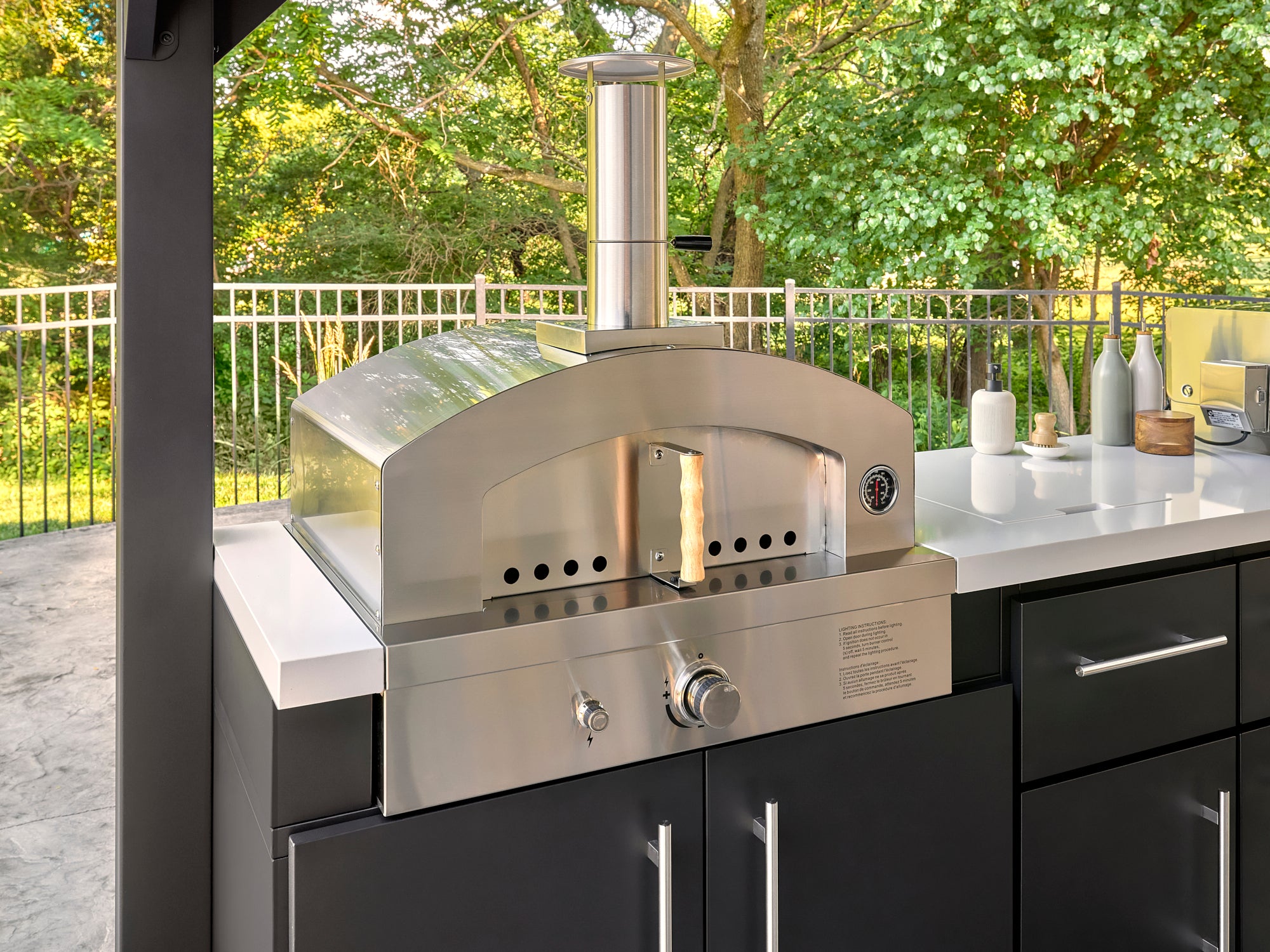 Stainless steel artisan pizza oven with dome lid and chimney built into Lancaster outdoor kitchen with countertop.