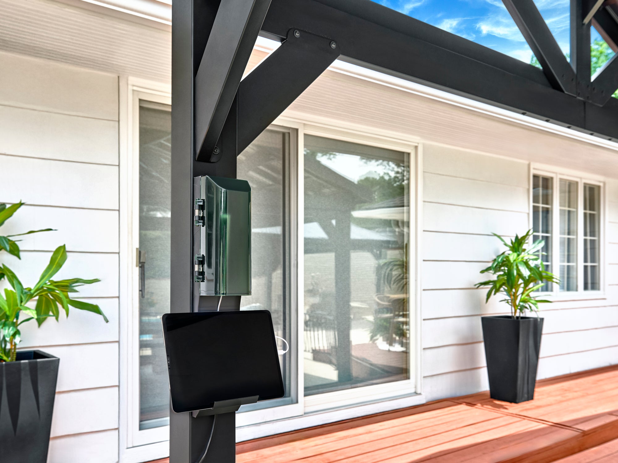 Tablet mounted on power port attached to black Lancaster steel gazebo frame post on wooden deck.