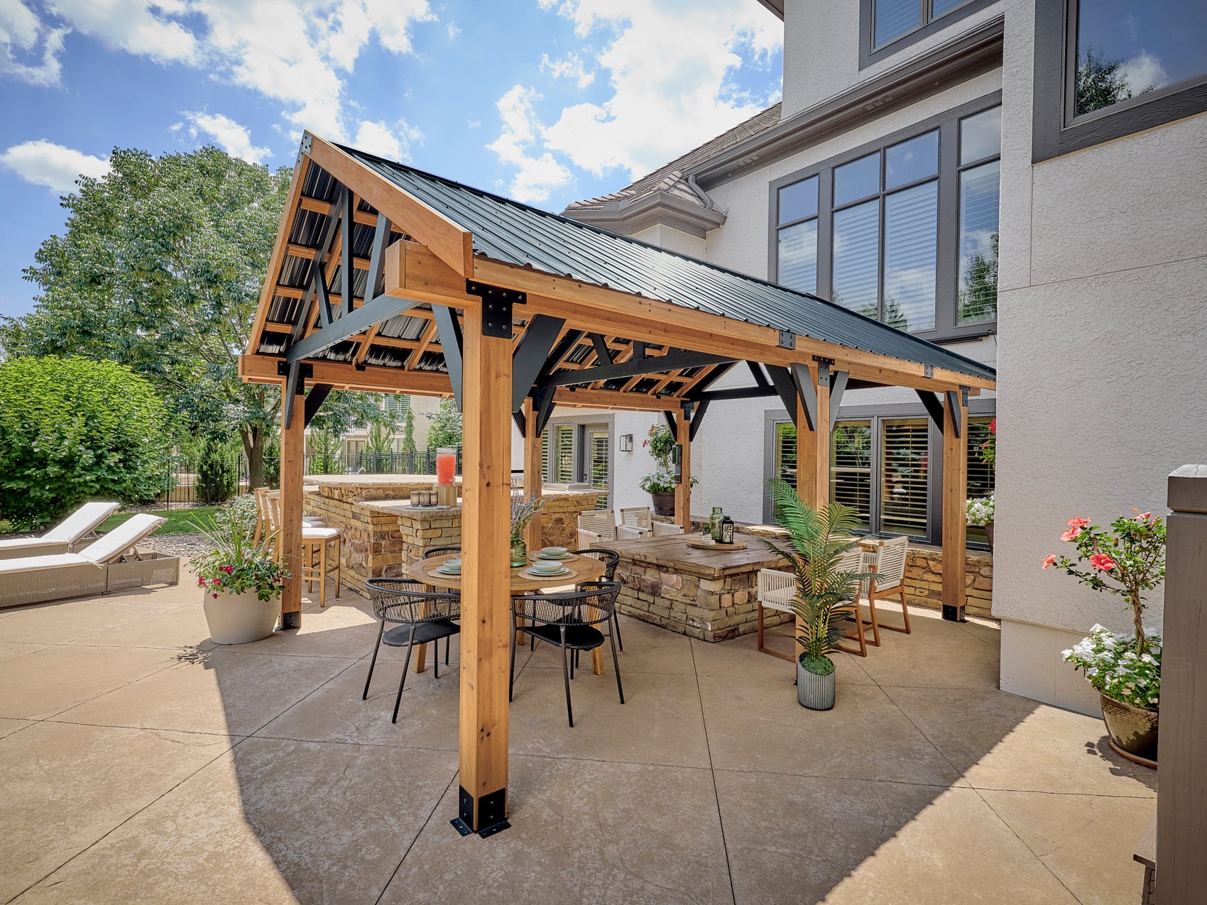 Cedar gazebo with metal roof over outdoor dining and bar area showcasing gazebo ideas for backyard entertaining.