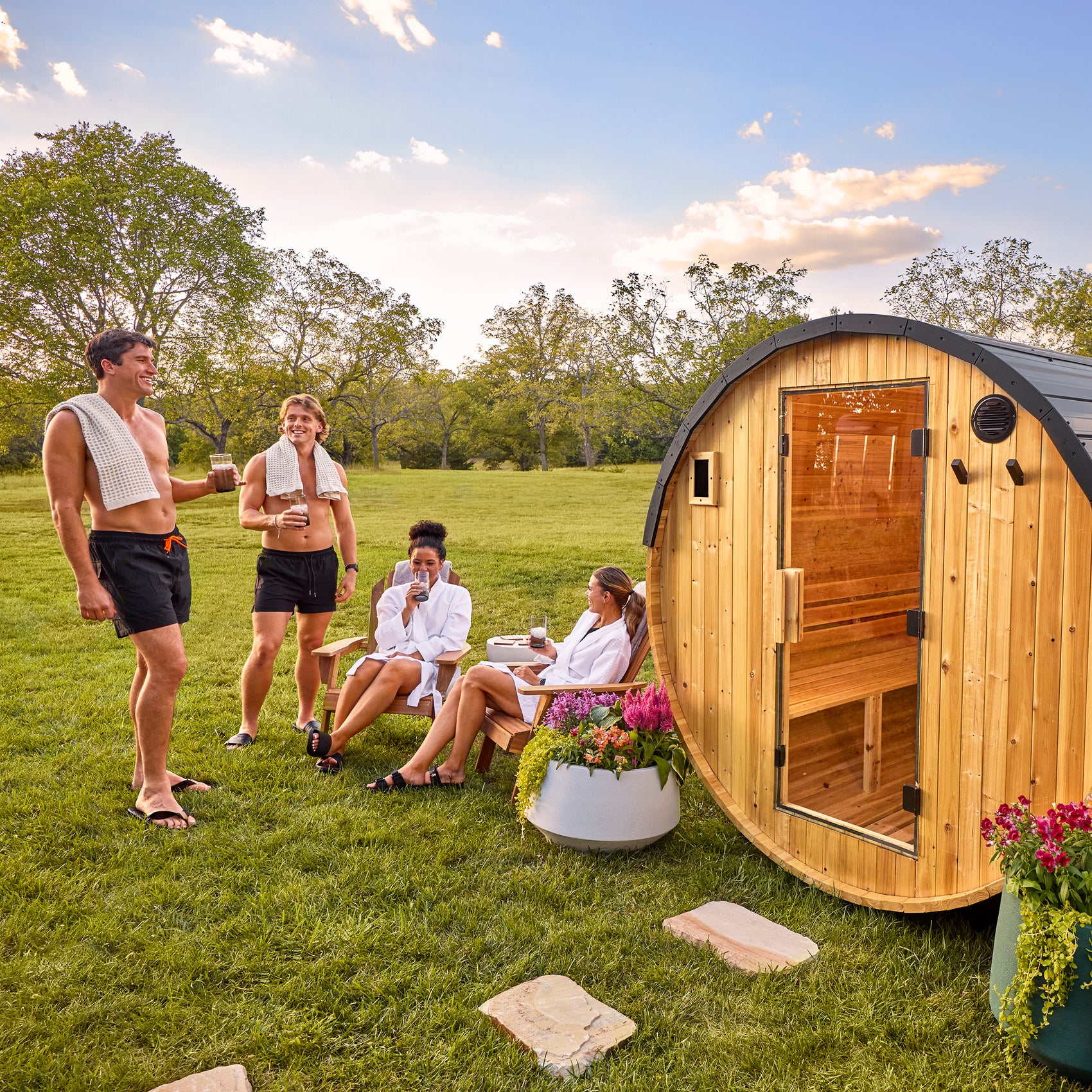 Group gathering around the 4-6 person Paxton cedar barrel backyard sauna in sunny setting