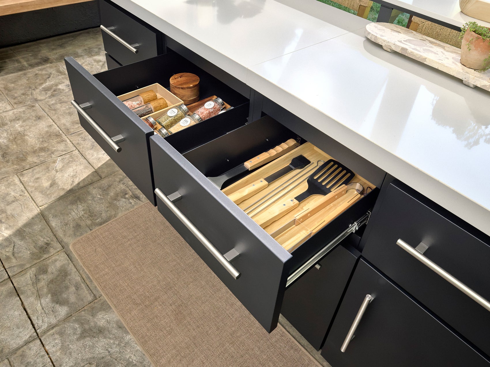 Black powder-coated steel drawers with Emory outdoor kitchen storage with bamboo utensil organizer and spice containers.
