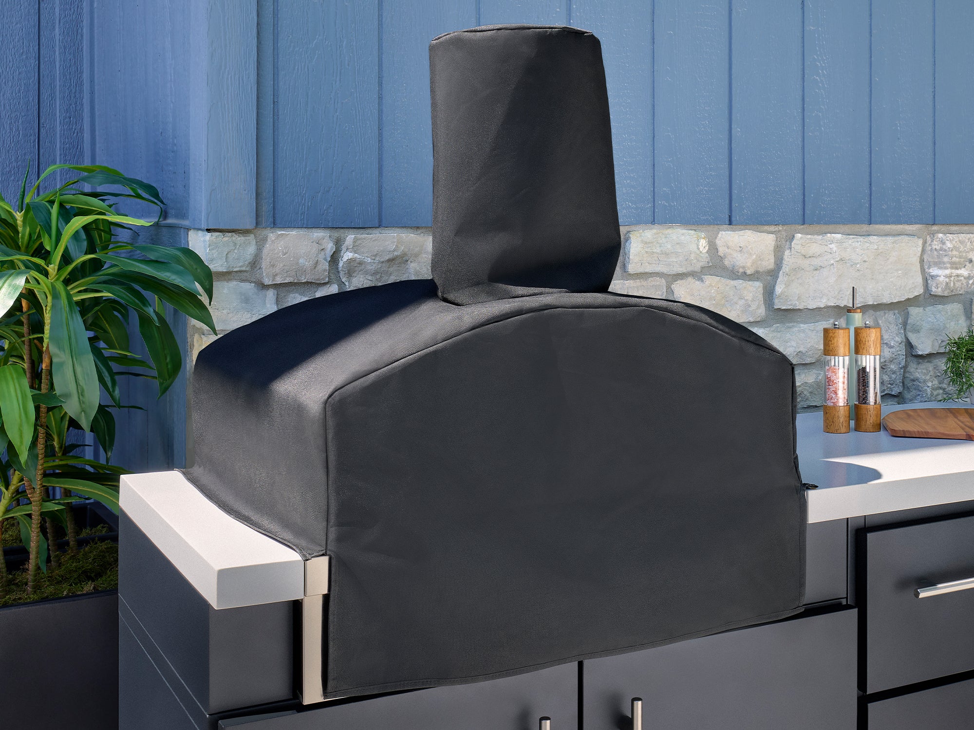 Weatherproof cover on outdoor pizza oven built into backyard kitchen with galvanized steel cabinets and countertop.