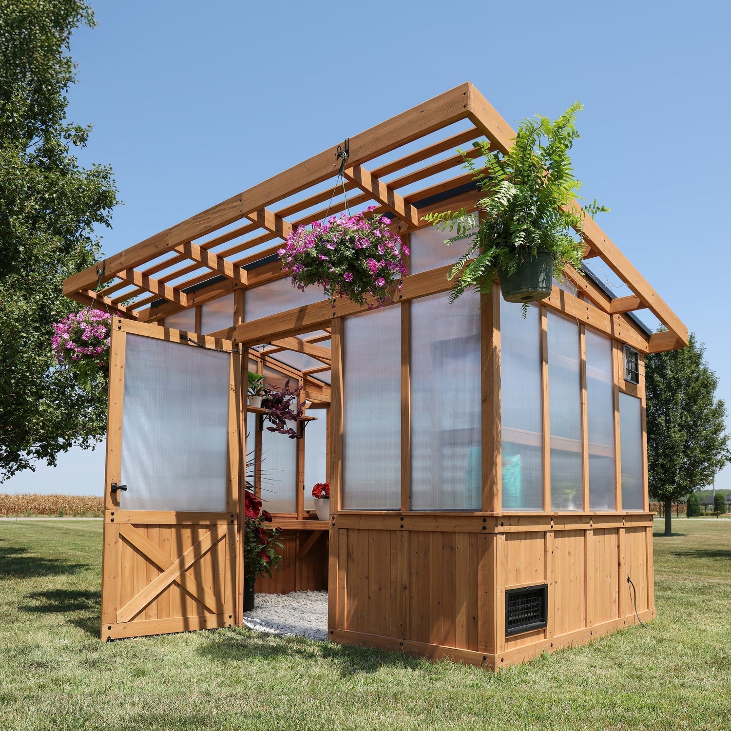 Backyard Discovery Poppy cedar greenhouse with polycarbonate panels and pergola-style roof overhang.
