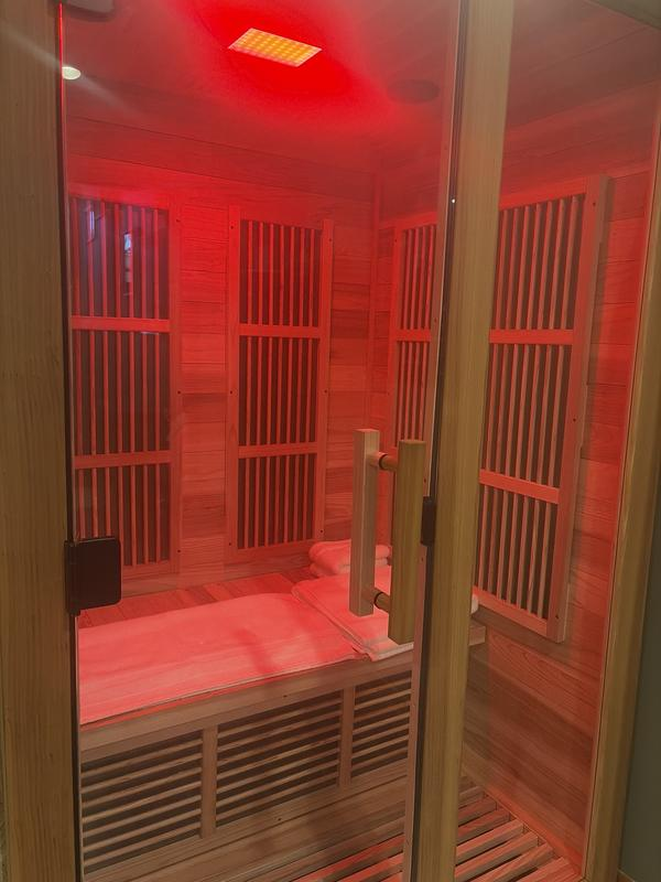 Infrared sauna with red light inside a wooden room